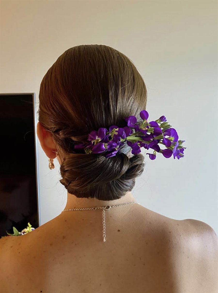 Sleek low bun with purple sweet pea flowers